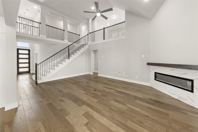 1347 Overton St, Frisco, TX 75036 - unfurnished living room featuring a high ceiling, ceiling fan, a fireplace, hardwood / wood-style floors, and stairs