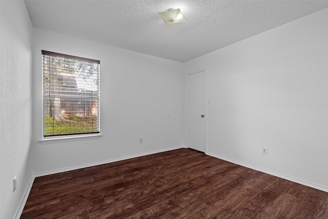 unfurnished room with dark hardwood / wood-style flooring and a textured ceiling