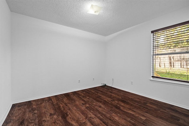 empty room with a textured ceiling and dark wood-type flooring