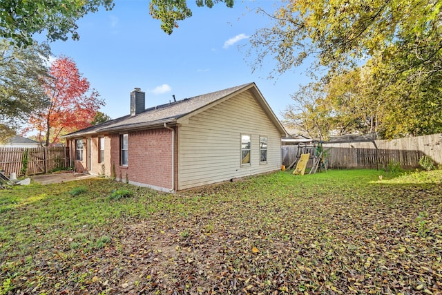 back of house featuring a playground and a lawn