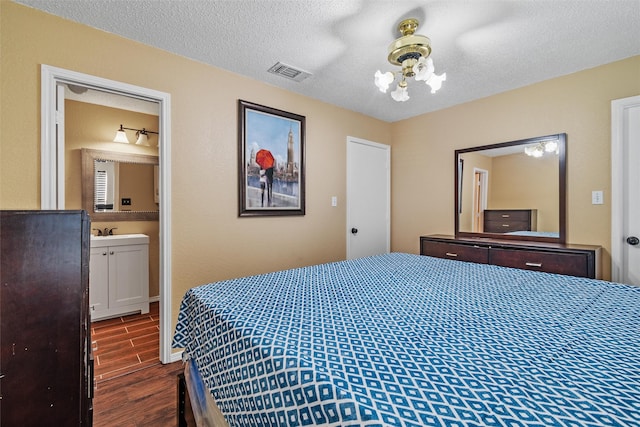 bedroom with dark hardwood / wood-style floors, sink, a textured ceiling, and ensuite bath