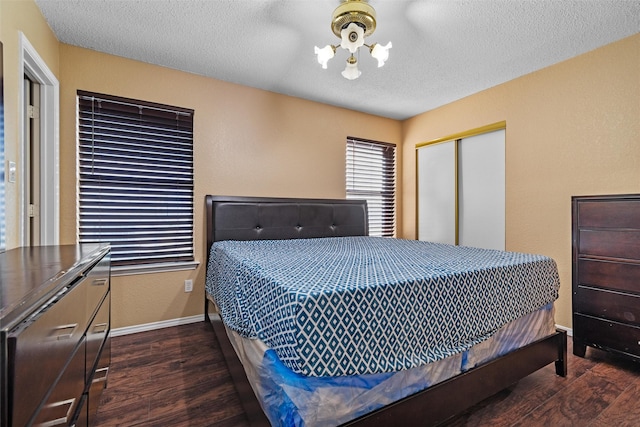 bedroom with dark wood-type flooring, a chandelier, a closet, and a textured ceiling