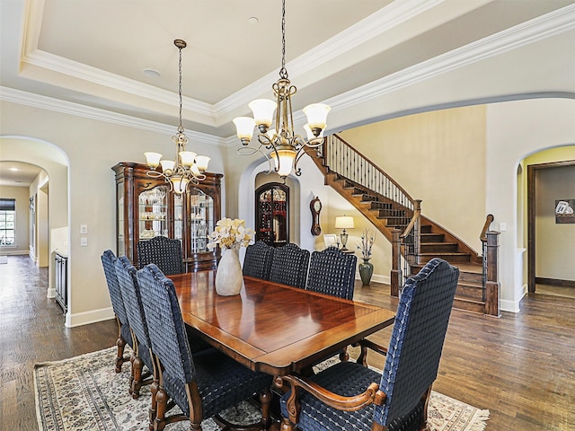 dining area with a chandelier, dark hardwood / wood-style flooring, a raised ceiling, and ornamental molding