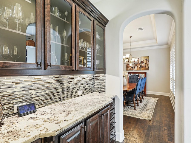 bar with dark brown cabinets, dark hardwood / wood-style flooring, tasteful backsplash, and an inviting chandelier