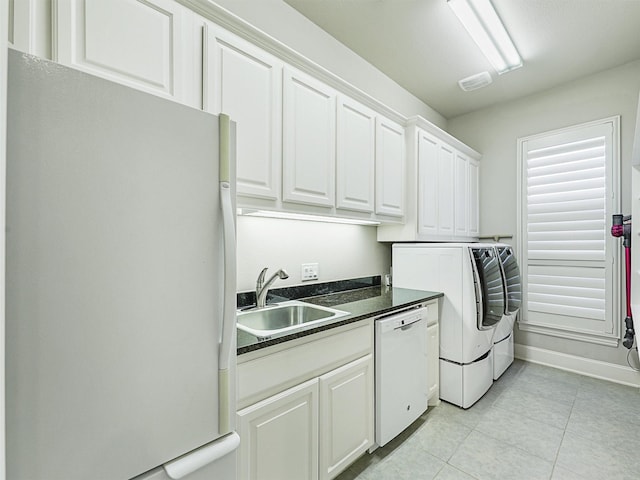 washroom with cabinets, light tile patterned floors, separate washer and dryer, and sink