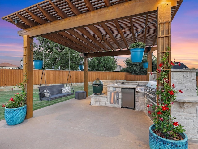 patio terrace at dusk with exterior kitchen and a pergola