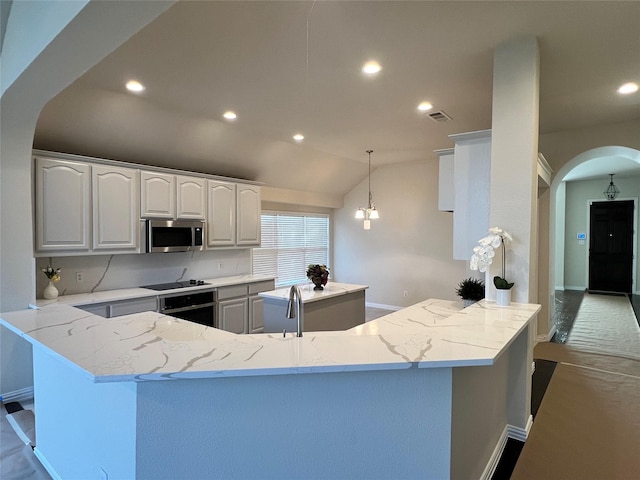 kitchen featuring pendant lighting, lofted ceiling, black appliances, light stone countertops, and white cabinetry