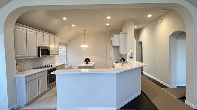 kitchen featuring lofted ceiling, white cabinets, hanging light fixtures, kitchen peninsula, and stainless steel appliances