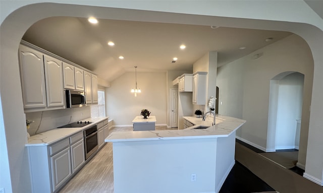 kitchen featuring light wood-type flooring, light stone counters, gray cabinetry, a chandelier, and a center island