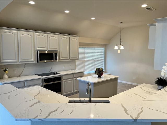 kitchen featuring light stone counters, a kitchen island, stainless steel appliances, and vaulted ceiling