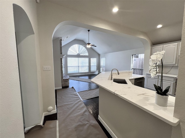 kitchen with light stone counters, sink, dishwasher, white cabinets, and lofted ceiling