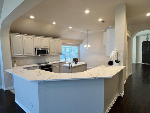 kitchen with dark hardwood / wood-style flooring, stainless steel appliances, vaulted ceiling, white cabinetry, and hanging light fixtures