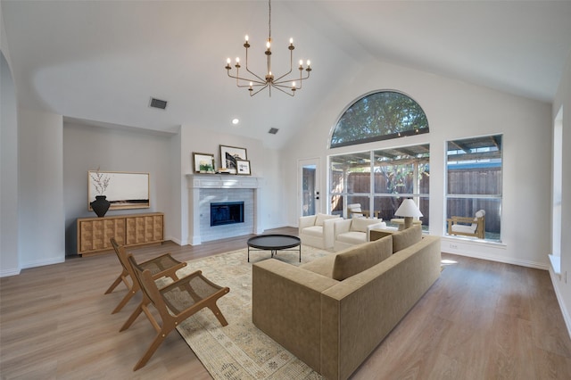 living room featuring an inviting chandelier, high vaulted ceiling, and light wood-type flooring