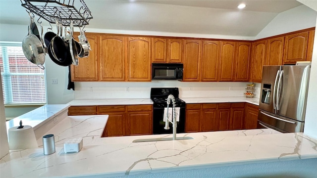 1700 Warm Springs Dr, Allen, TX 75002 - kitchen with light stone countertops, vaulted ceiling, brown cabinetry, and black appliances