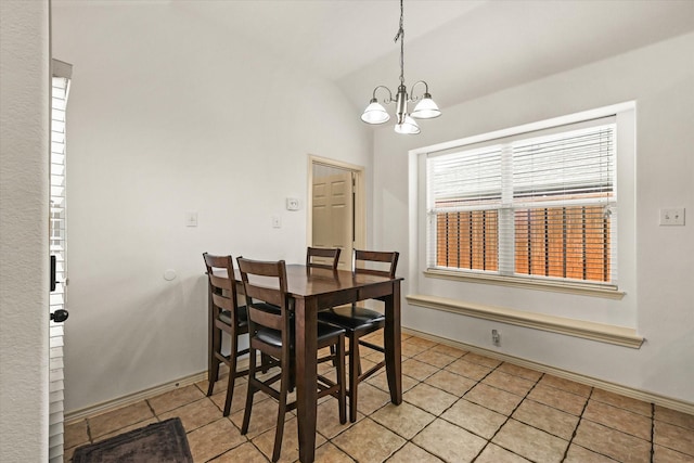 tiled dining space with lofted ceiling and an inviting chandelier