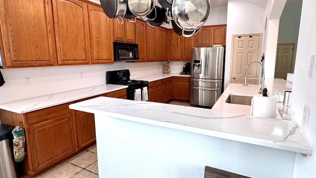 1700 Warm Springs Dr, Allen, TX 75002 - kitchen featuring a peninsula, a sink, brown cabinetry, black appliances, and light stone counters