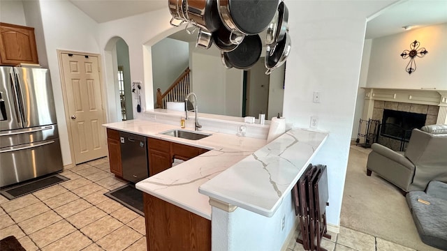 1700 Warm Springs Dr, Allen, TX 75002 - kitchen featuring light tile patterned flooring, a sink, a peninsula, arched walkways, and appliances with stainless steel finishes
