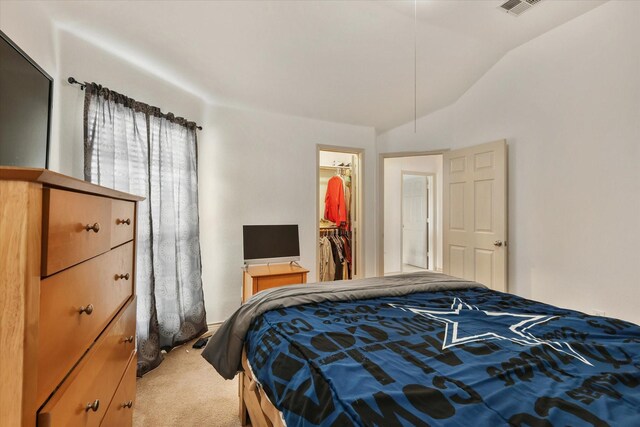 carpeted bedroom with a spacious closet, a closet, and lofted ceiling