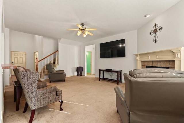 living room with a tile fireplace, light colored carpet, and ceiling fan