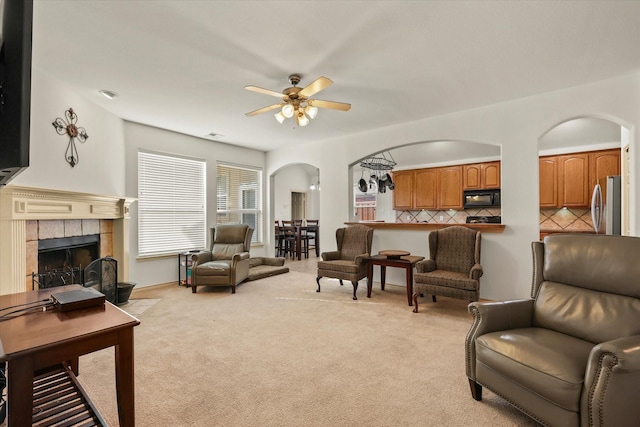 carpeted living room with a tile fireplace and ceiling fan