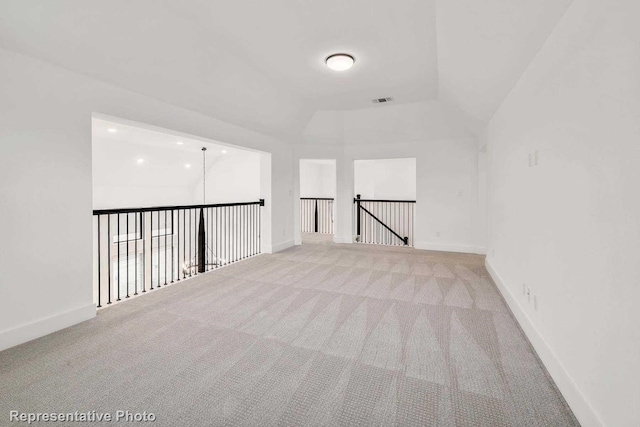 carpeted empty room with vaulted ceiling