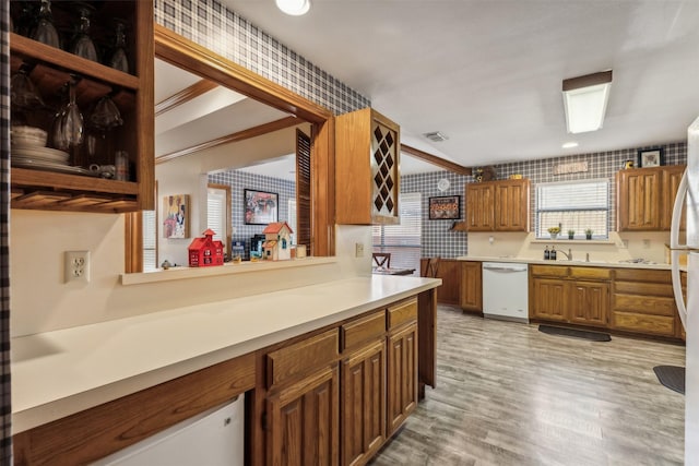 kitchen with crown molding, light hardwood / wood-style flooring, white dishwasher, and sink