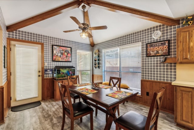 dining space featuring a wealth of natural light, wooden walls, and light hardwood / wood-style floors