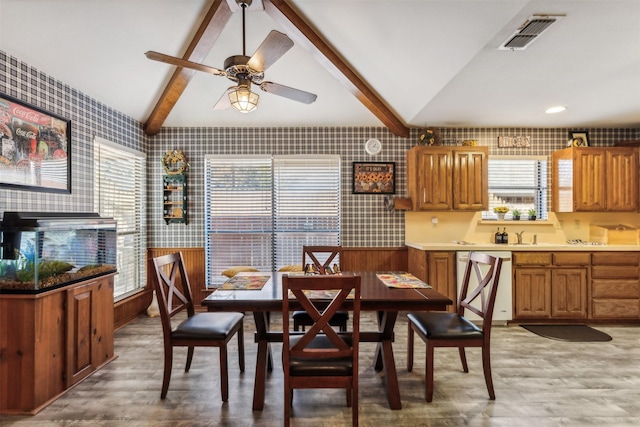 dining room featuring wood-type flooring, vaulted ceiling with beams, plenty of natural light, and ceiling fan