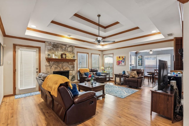 living room with ceiling fan, a raised ceiling, crown molding, light hardwood / wood-style floors, and a fireplace