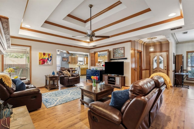 living room featuring light hardwood / wood-style floors, ornamental molding, and a tray ceiling