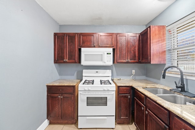 kitchen with light tile patterned floors, white appliances, light stone counters, and sink