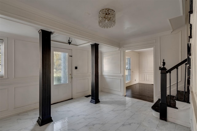 entryway with ornamental molding, decorative columns, and a wealth of natural light