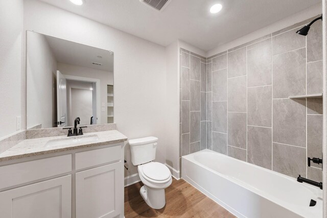 full bathroom with vanity, toilet, tiled shower / bath, and hardwood / wood-style flooring