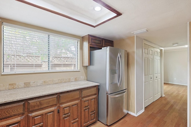 kitchen featuring stainless steel fridge, light stone countertops, and light wood-type flooring