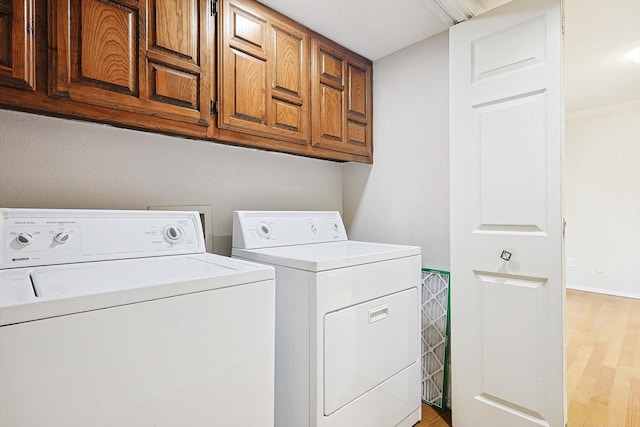 laundry room with washer and clothes dryer, cabinets, and light hardwood / wood-style flooring