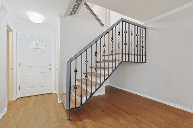 stairway with hardwood / wood-style floors and ornamental molding