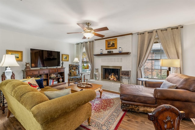 living room featuring ceiling fan, dark hardwood / wood-style flooring, and a brick fireplace