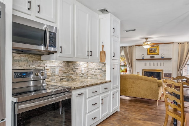 kitchen with light stone countertops, appliances with stainless steel finishes, white cabinetry, and a wealth of natural light