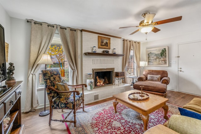 living room featuring a brick fireplace, ceiling fan, and light hardwood / wood-style flooring