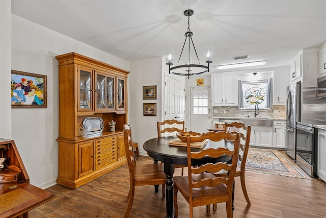 dining area featuring sink, a notable chandelier, and hardwood / wood-style flooring