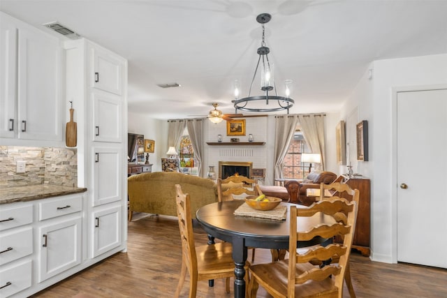 dining space with ceiling fan, a fireplace, and hardwood / wood-style flooring