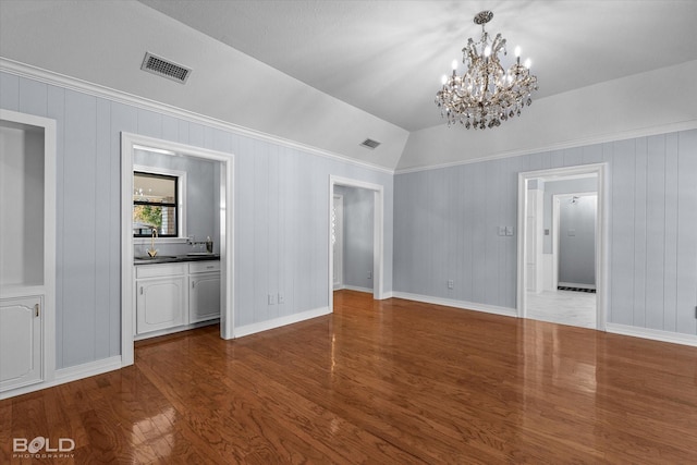 interior space with hardwood / wood-style flooring, vaulted ceiling, and a notable chandelier