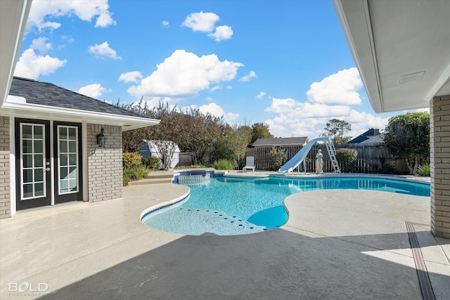 view of swimming pool with french doors, a water slide, and a patio area