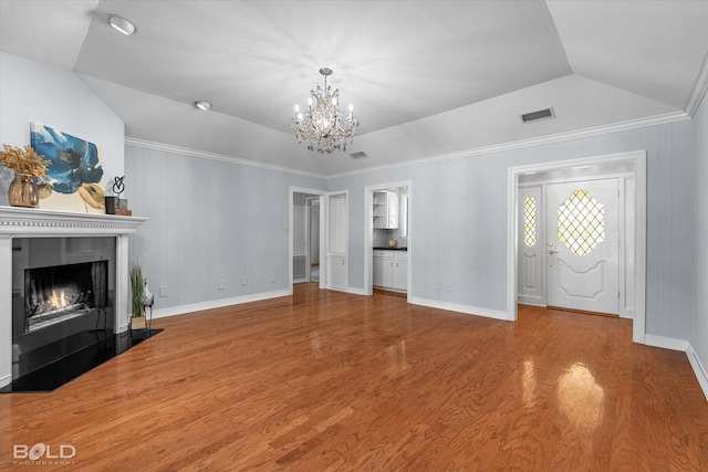 unfurnished living room with hardwood / wood-style flooring, lofted ceiling, and a chandelier