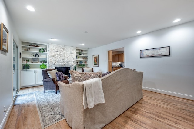 living room featuring built in shelves, a fireplace, and light hardwood / wood-style flooring