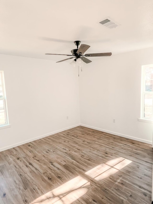 empty room with hardwood / wood-style flooring, ceiling fan, and a healthy amount of sunlight