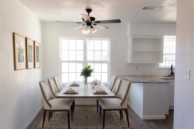 dining area featuring ceiling fan, sink, and wood-type flooring