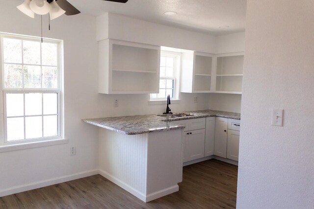 kitchen with sink, dark hardwood / wood-style floors, ceiling fan, light stone counters, and white cabinetry