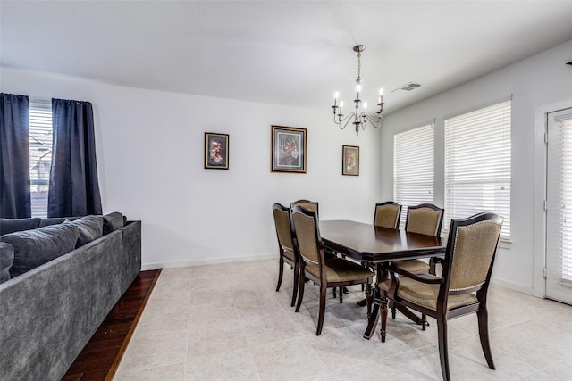 tiled dining space featuring plenty of natural light and a notable chandelier