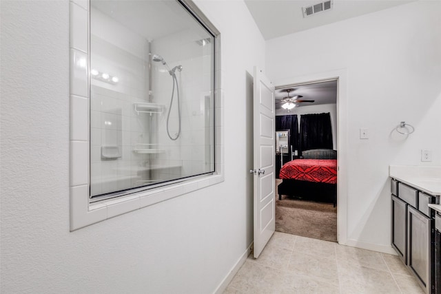 bathroom with tile patterned flooring, ceiling fan, tiled shower, and vanity